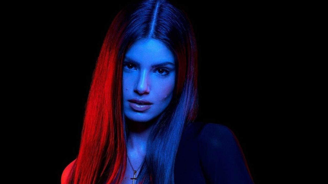 Camila Queiroz posando para foto com cabelo dividido no meio em fundo escuro