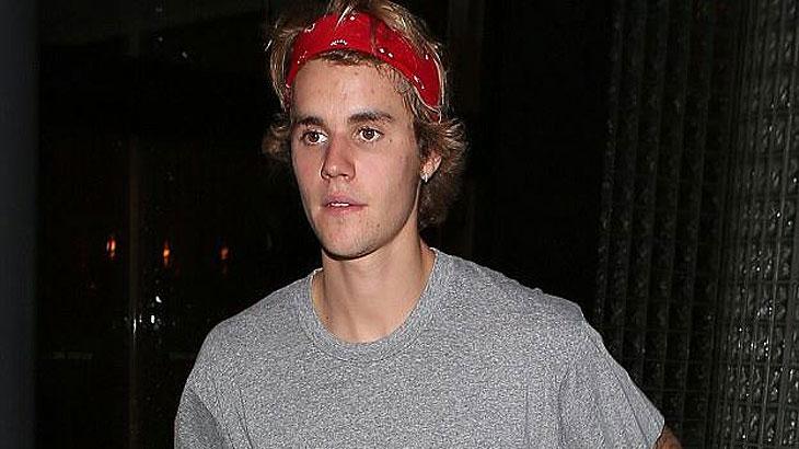 Justin Bieber com faixa vermelha na cabeça