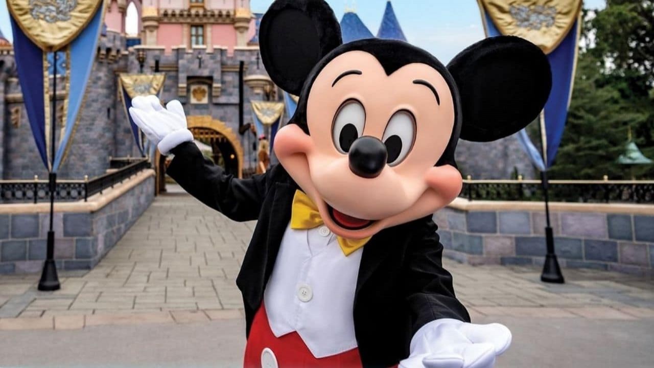 Mickey Mouse posando para foto no parque da Disney com os braços abertos