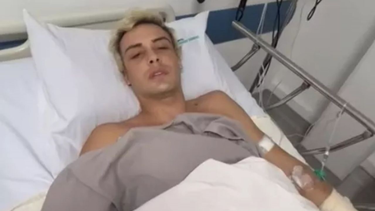 Bruno Krupp com expressão triste, deitado em cama de hospital e olhando para a câmera