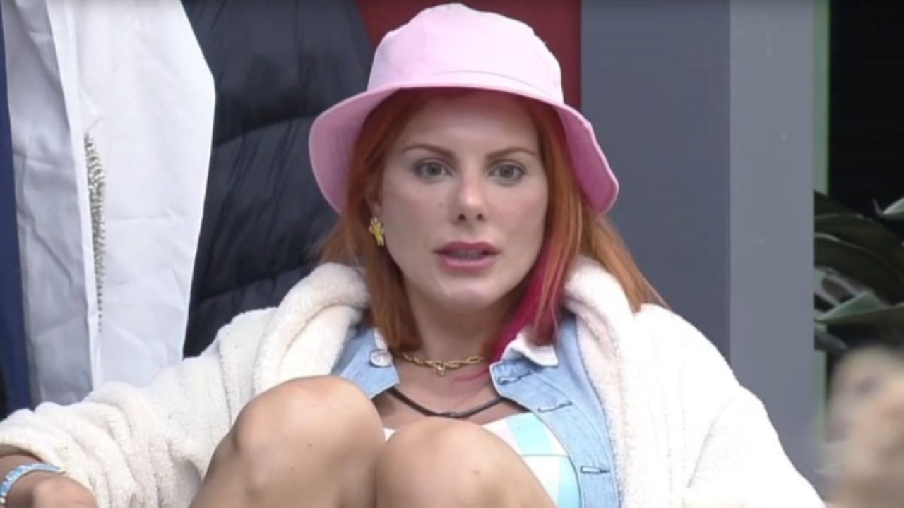 Deborah Albuquerque de roupa azul, chapéu rosa e roupão branco