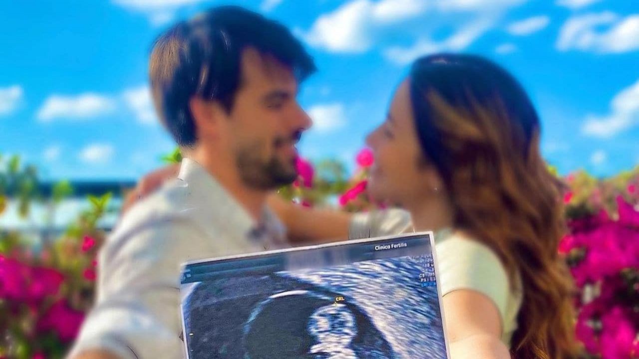 Leandro Gléria e Renata Dominguez em segundo plano, se olhando e segurando foto de ultrassom, que está no foco