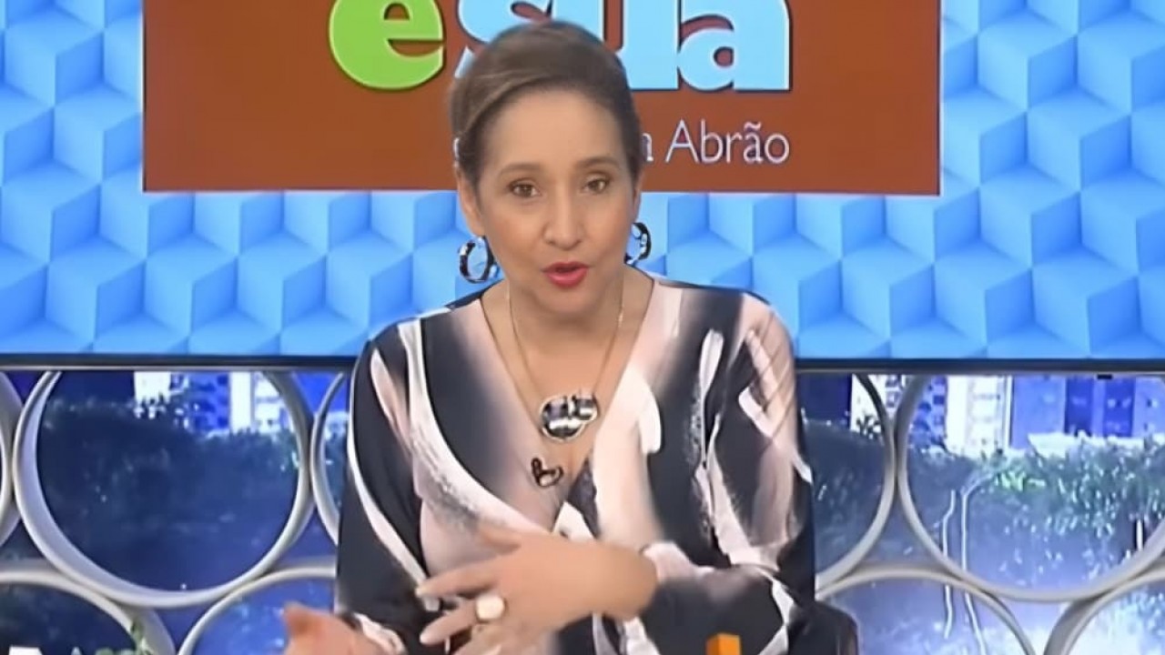 Sonia Abrão em seu A Tarde é Sua, de cabelo preso e roupa estampada, falando e gesticulando