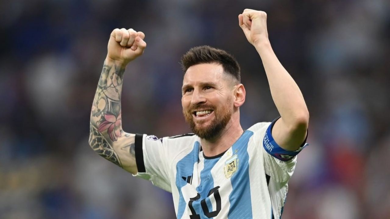 Lionel Messi com camisa da Argentina, comemorando e sorrindo com os braços para o alto