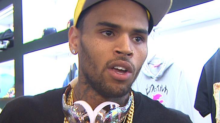 Chris Brown de boné amarelo e fone de ouvido ostentador