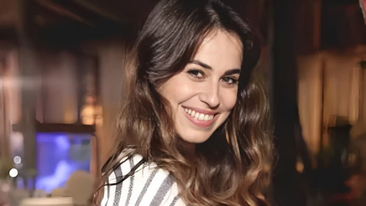 Daniela Escobar sorrindo, de cabelo solto e roupa listrada