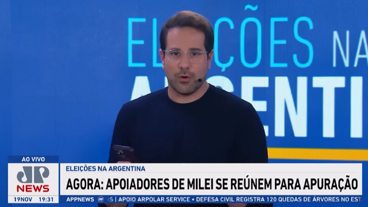 Tela da Jovem Pan News com Paulo Mathias de roupa preta e óculos, falando