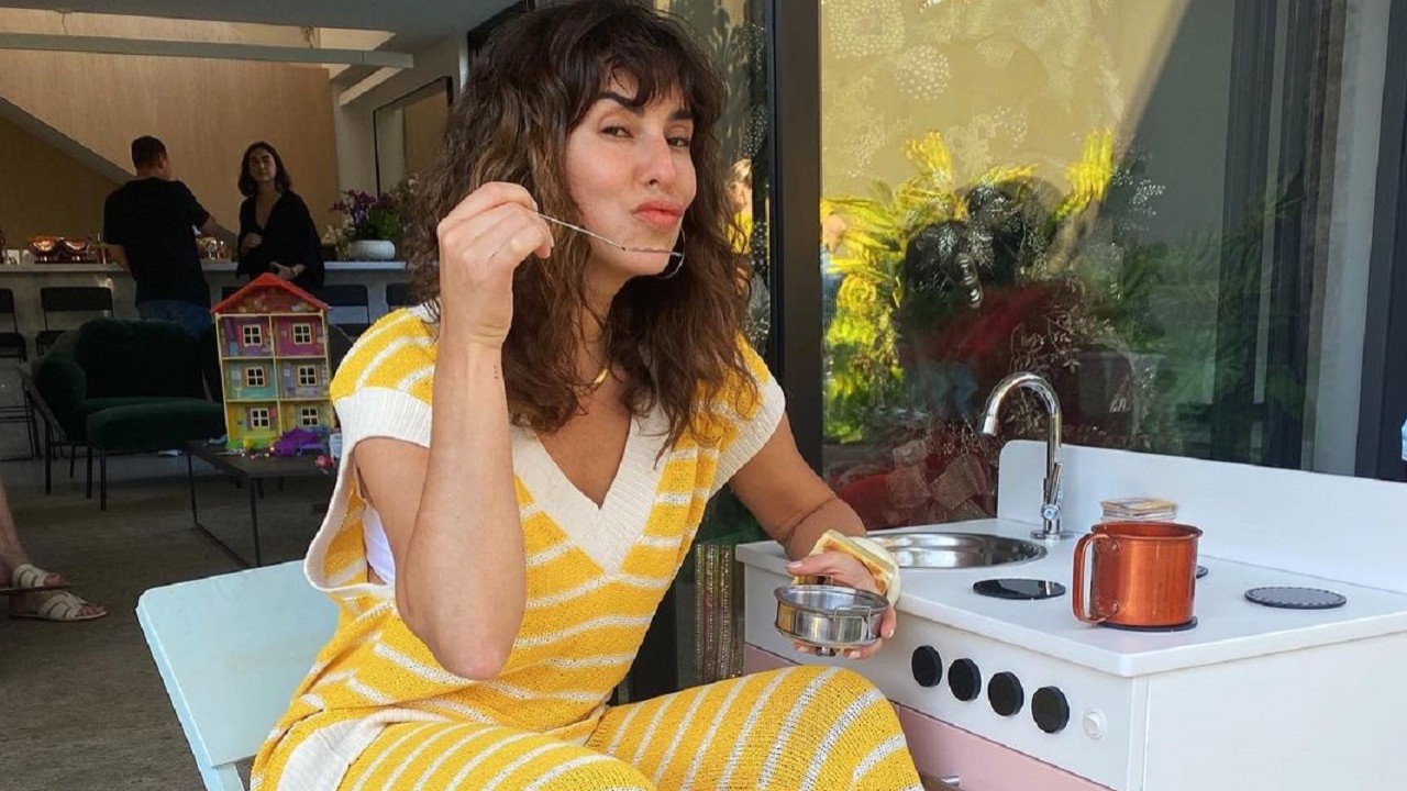 Fernanda Paes Leme sentada ao lado de uma pia de um fogão embutido