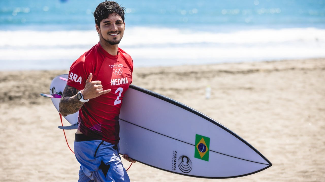 Gabriel Medina segurando prancha de surfe na praia