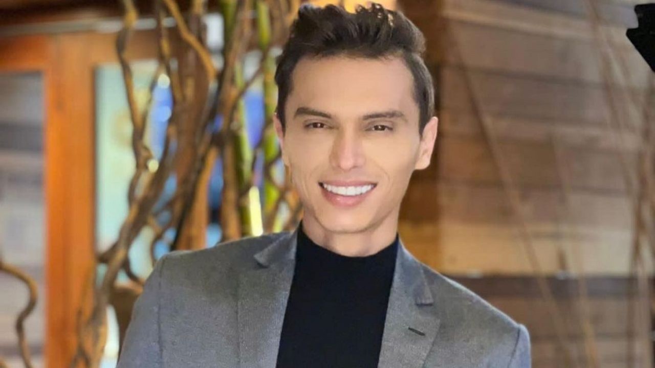 Gabriel Torres sorrindo, vestindo camisa preta e terno cinza