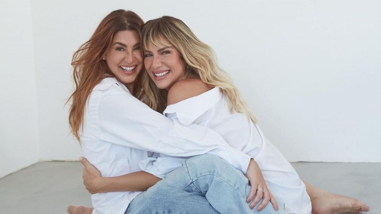 Giovanna Ewbank e Fernanda Paes Leme de roupas jeans e brancas, sorrindo, abraçadas