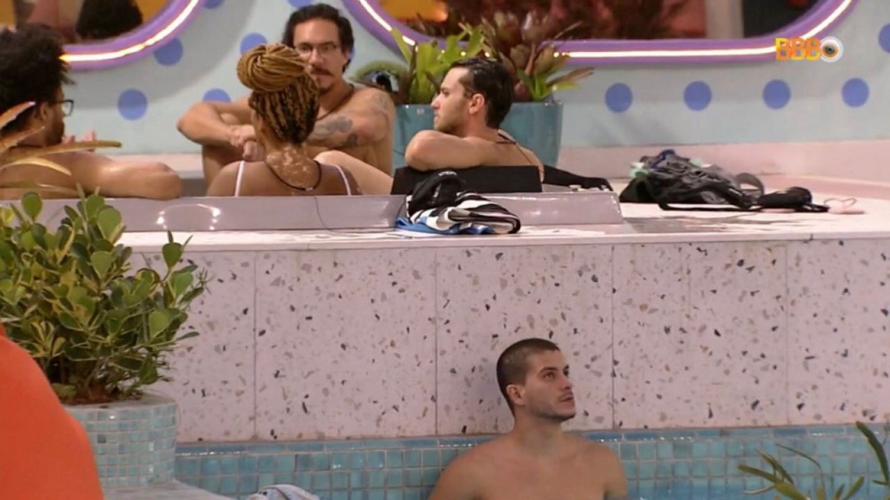 Arthur Aguiar ouvindo a conversa de participantes, que estão na jacuzzi, na piscina 