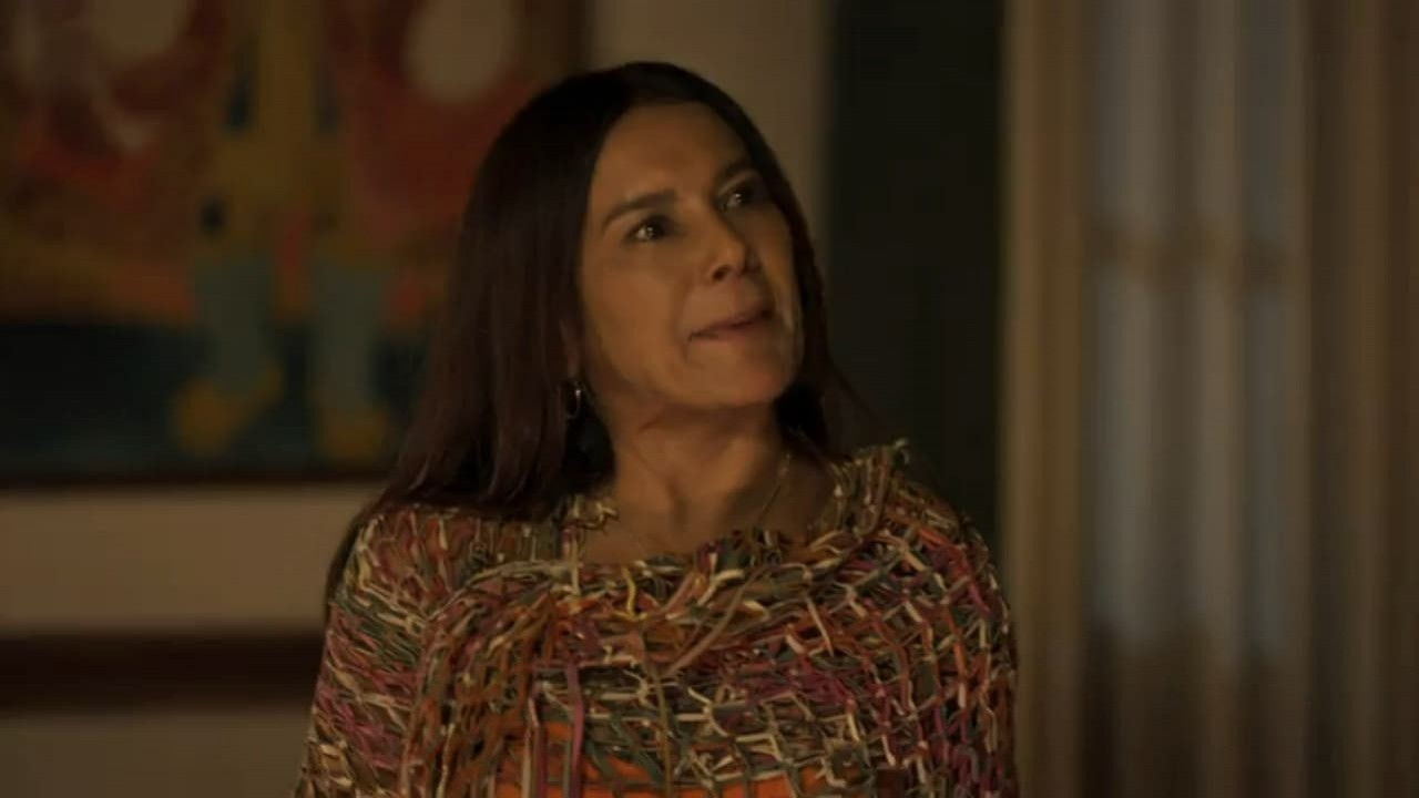 Dira Paes como Filó na novela Pantanal. Ela está em pé na sala da fazenda de José Leôncio