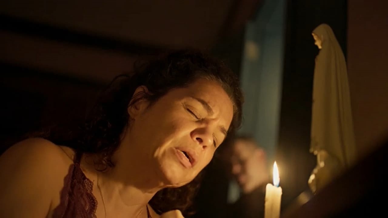 Isabel Teixeira como Maria Bruaca em Pantanal. Ela está de joelho e rezando para uma santa