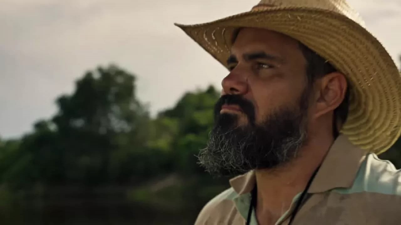 Juliano Cazarré como Alcides em Pantanal. Ele está na beira do rio