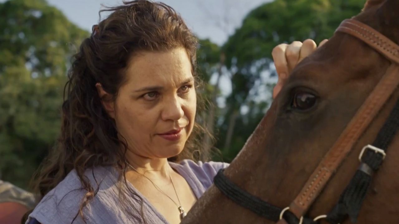 Isabel Teixeira em cena de Pantanal: atriz está caracterizada com Maria Bruaca e acaricia cavalo