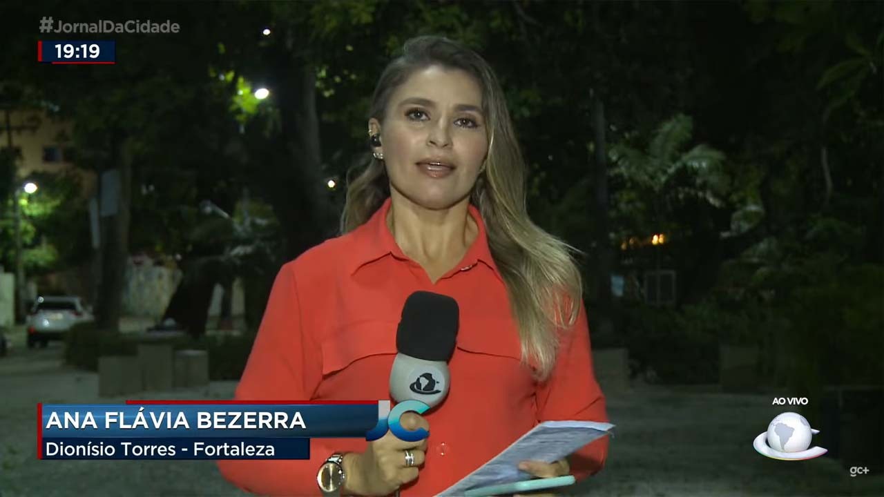 Ana Flávia Bezerra em entrada ao vivo, segurando microfone e com o celular e papel em outra mão