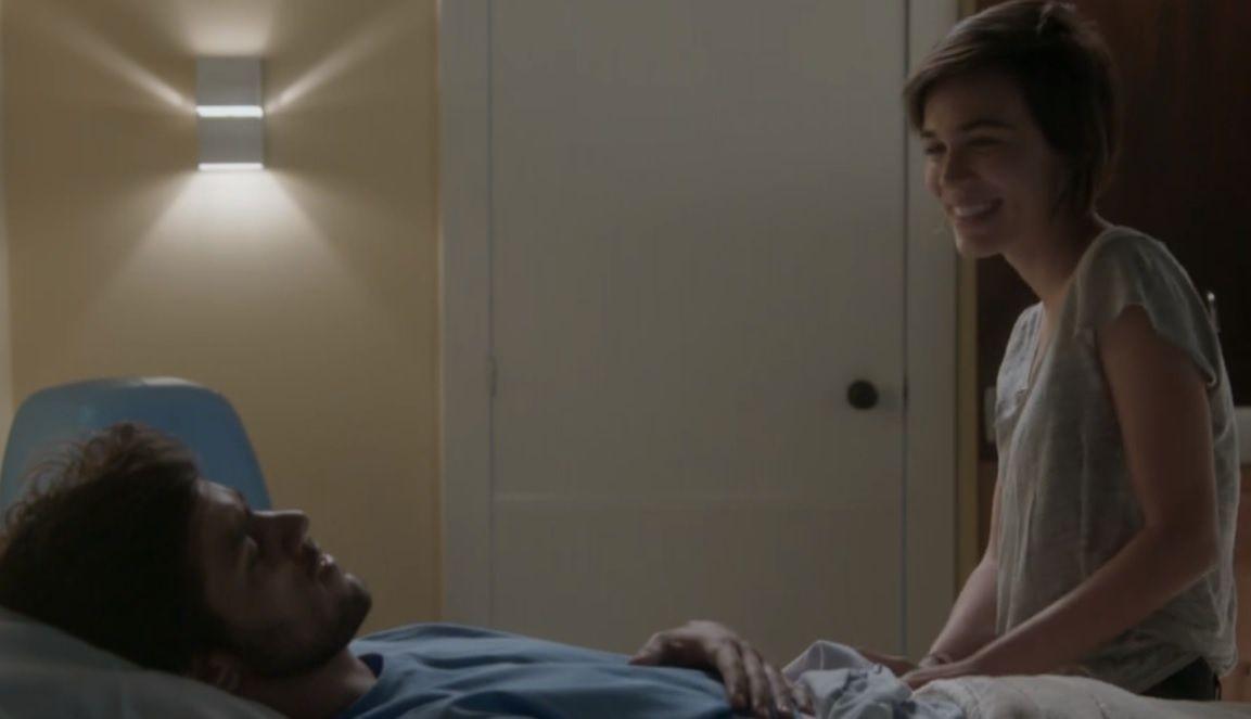 Deitado na cama do quarto de um hospital, Jonatas olha na direção de Leila que está sentada e sorrindo para o rapaz