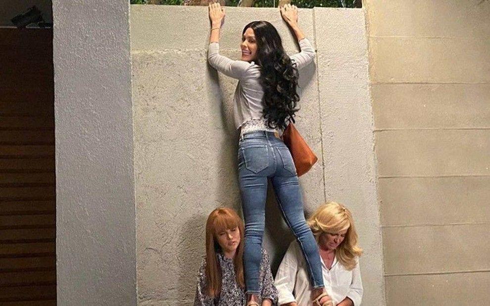 Kyra se apoiando em Luna e Alexia enquanto escala muro