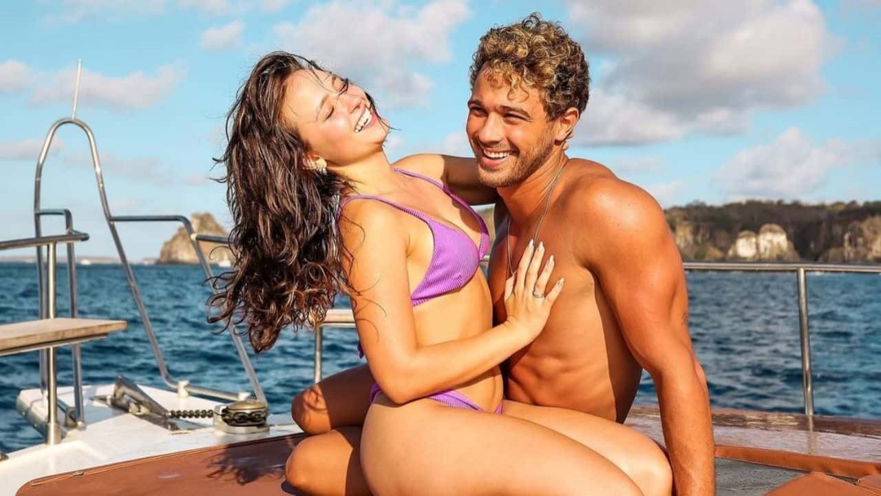 Larissa Manoela e André Luiz Frambach posando e sorrindo em barco