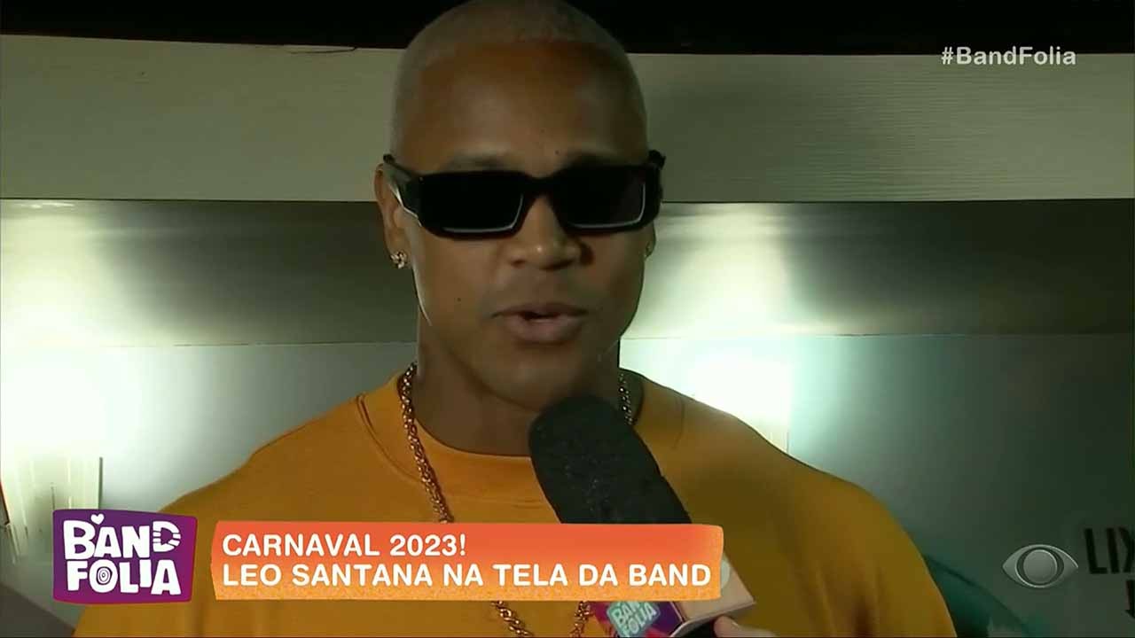 Léo Santana usando óculos com camisa laranja durante entrevista ao Band Folia 