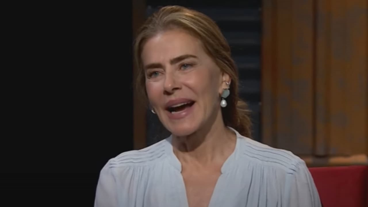 Maitê Proença no programa Provoca, de roupa social azul clara e cabelo preso, falando e rindo sem olhar para a câmera