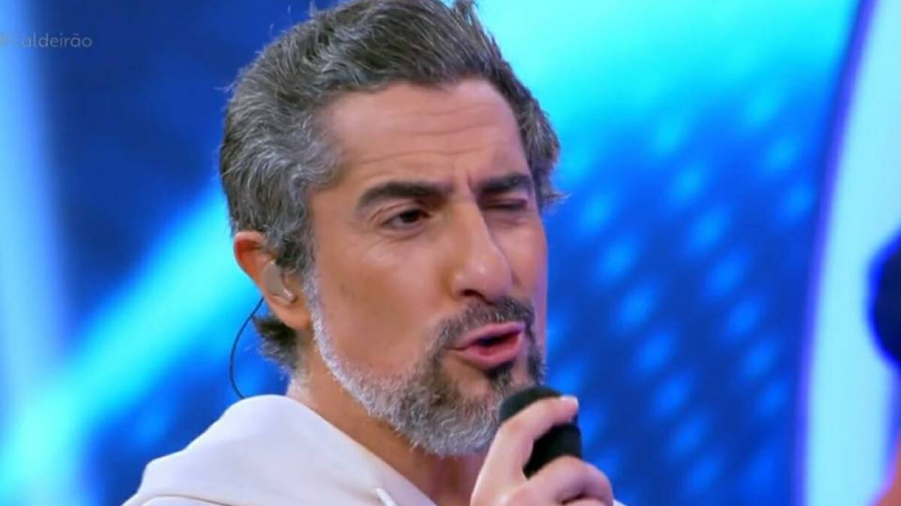 Marcos Mion com microfone falando no Caldeirão de moletom branco