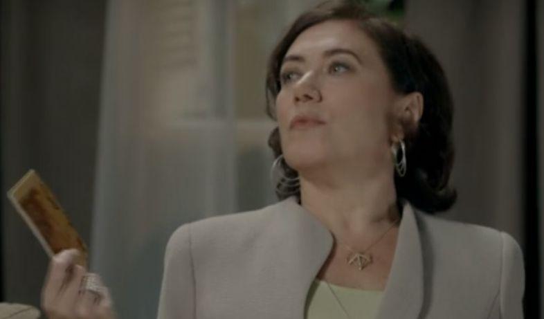 Maria Marta olha para Cristina com ar de superioridade e um talão de cheques na mão