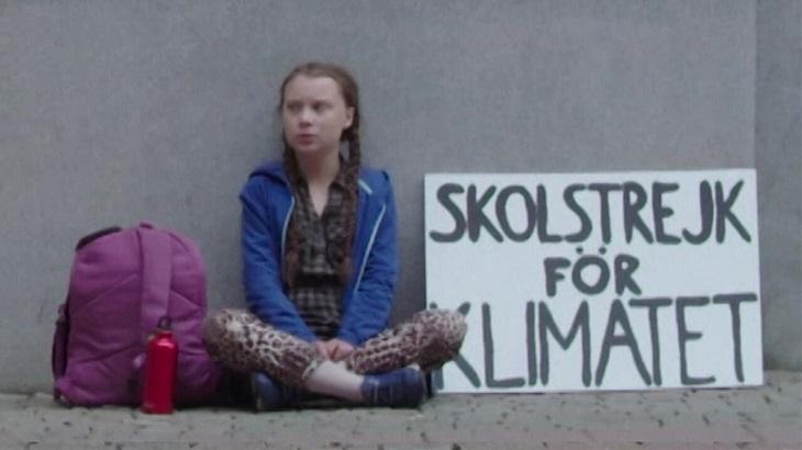 Greta Thunberg sentada em protesto