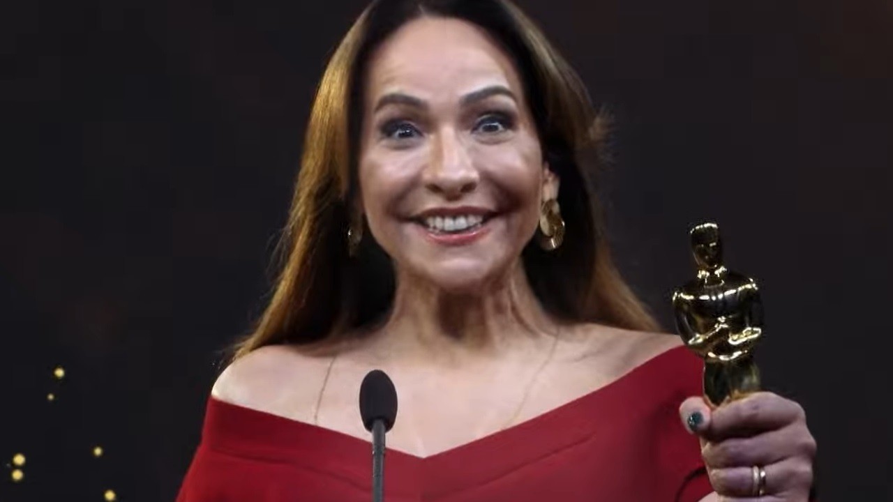 Vestida de vermelho, Maria Beltrão segura uma estatueta do Oscar na chamada da premiação para o Globoplay