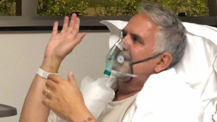 Orlando Morais acenando, com máscara de oxigênio, em leito hospítalar