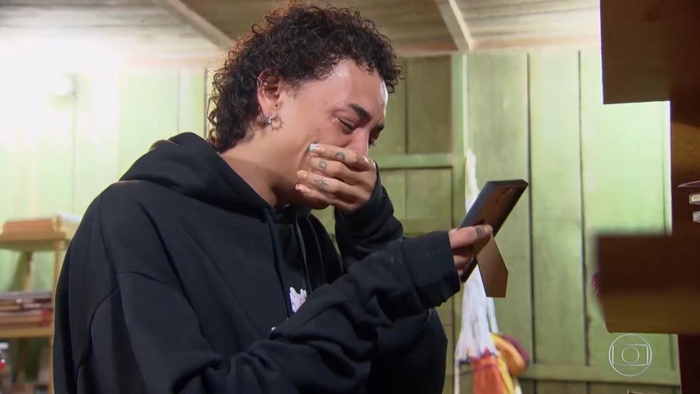 Pabllo Vittar chorando com celular na mão de moletom preto