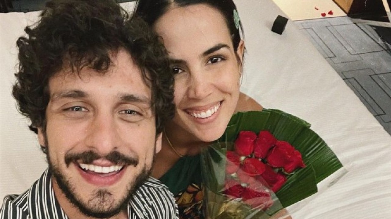 Pérola Faria sorrindo com um buquê de flores ao lado de Mario Bregieira