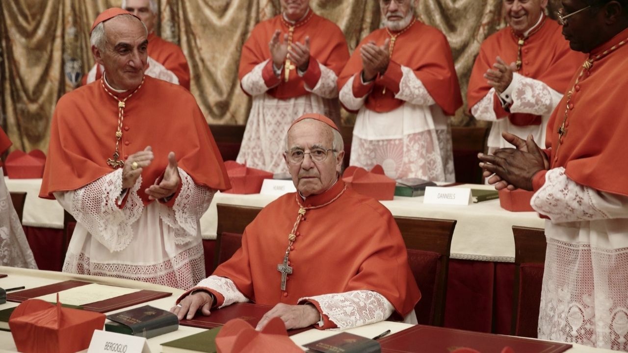 Cena do filme Pode Me Chamar de Francisco (2015), que mostra vários padres reunidos com batinas vermelhas
