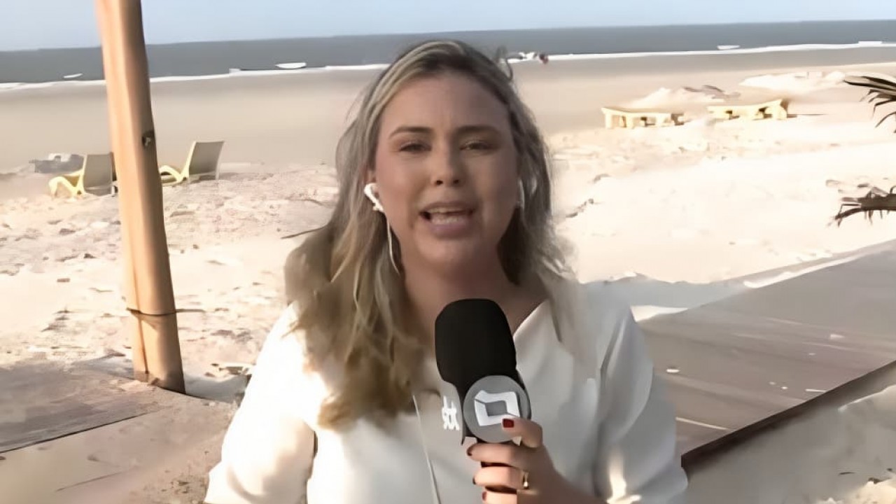 Repórter Jéssica Lima de blusa branca, falando em microfone, de cabelo solto