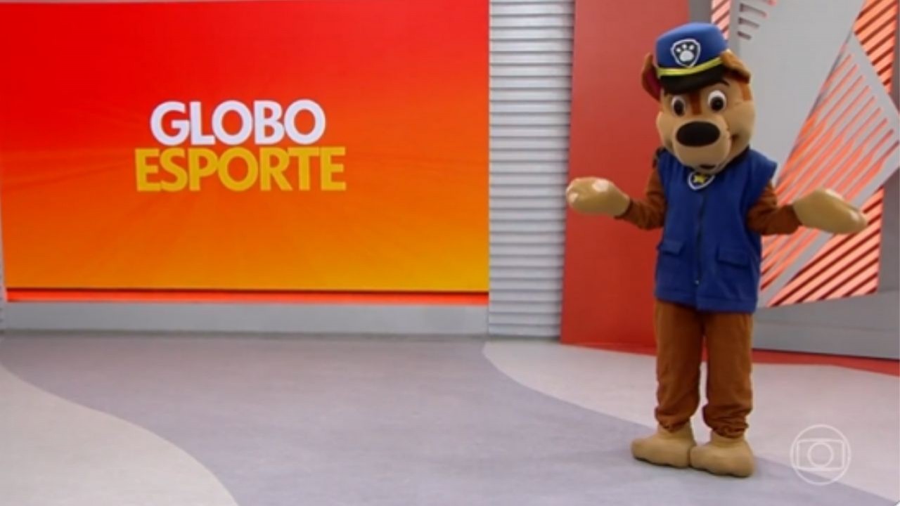 Sabrina Rocha vestida como o Chase, do desenho Patrulha Canina, no cenário do Globo Esporte