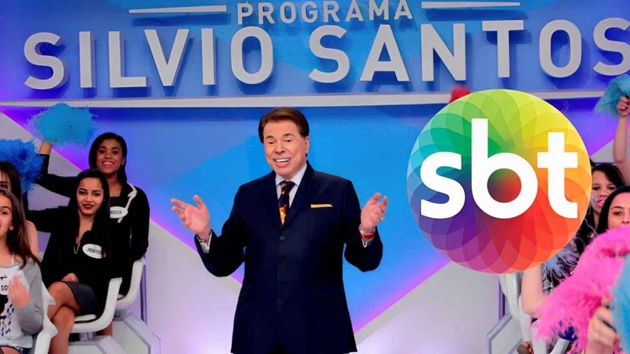 Silvio Santos com o logo do SBT ao lado