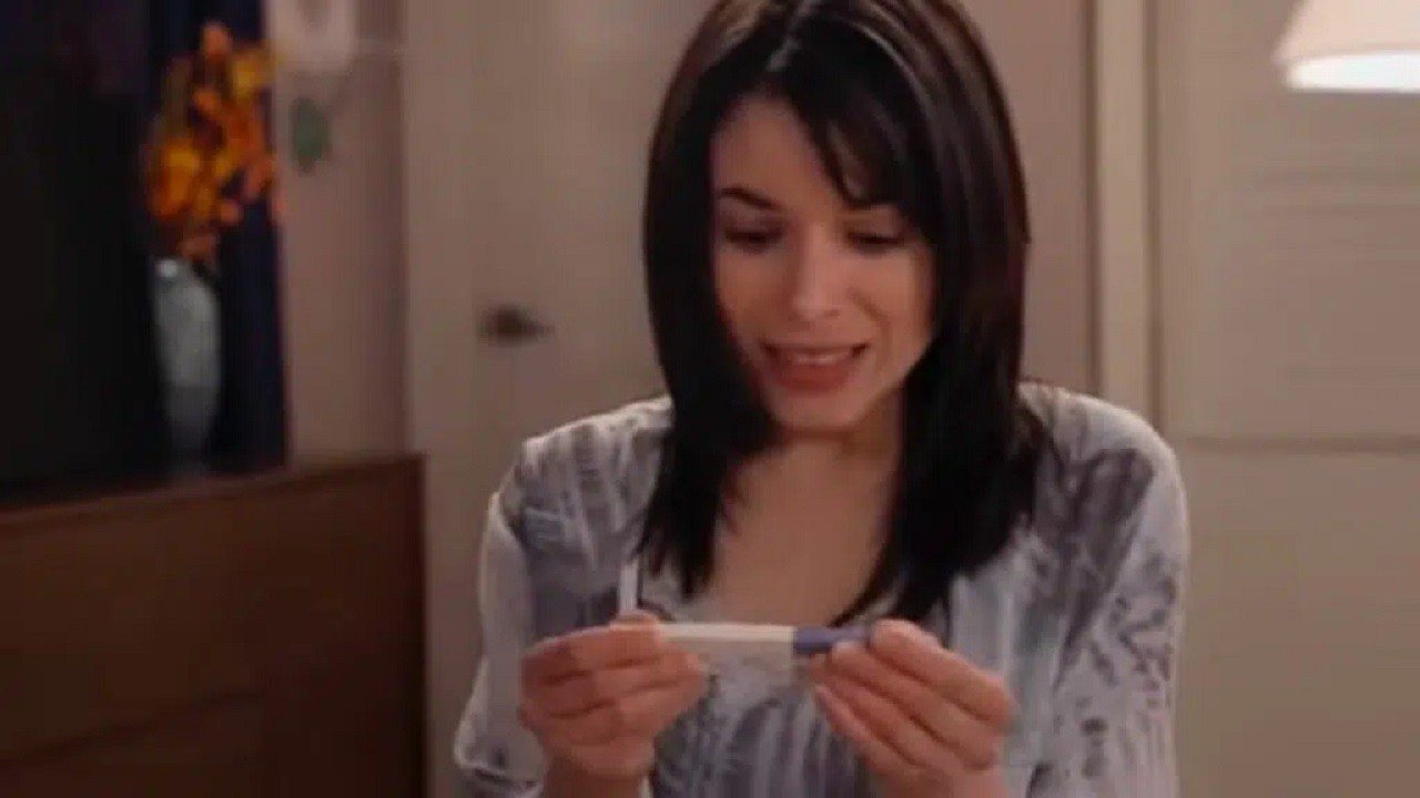Cena de Te Dou a Vida com Gina olhando para um teste de gravidez