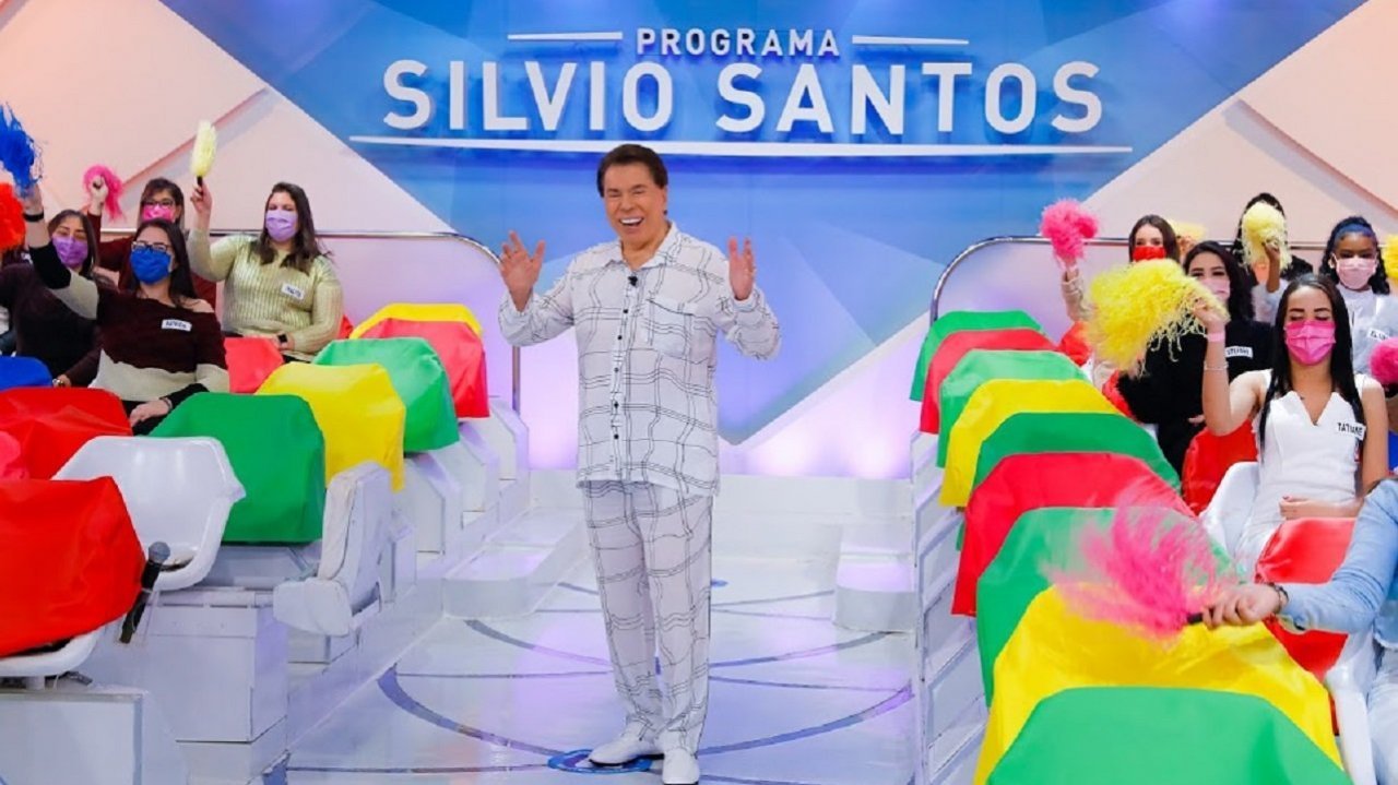 Silvio Santos de pijama na gravação do seu programa com o auditório ao fundo