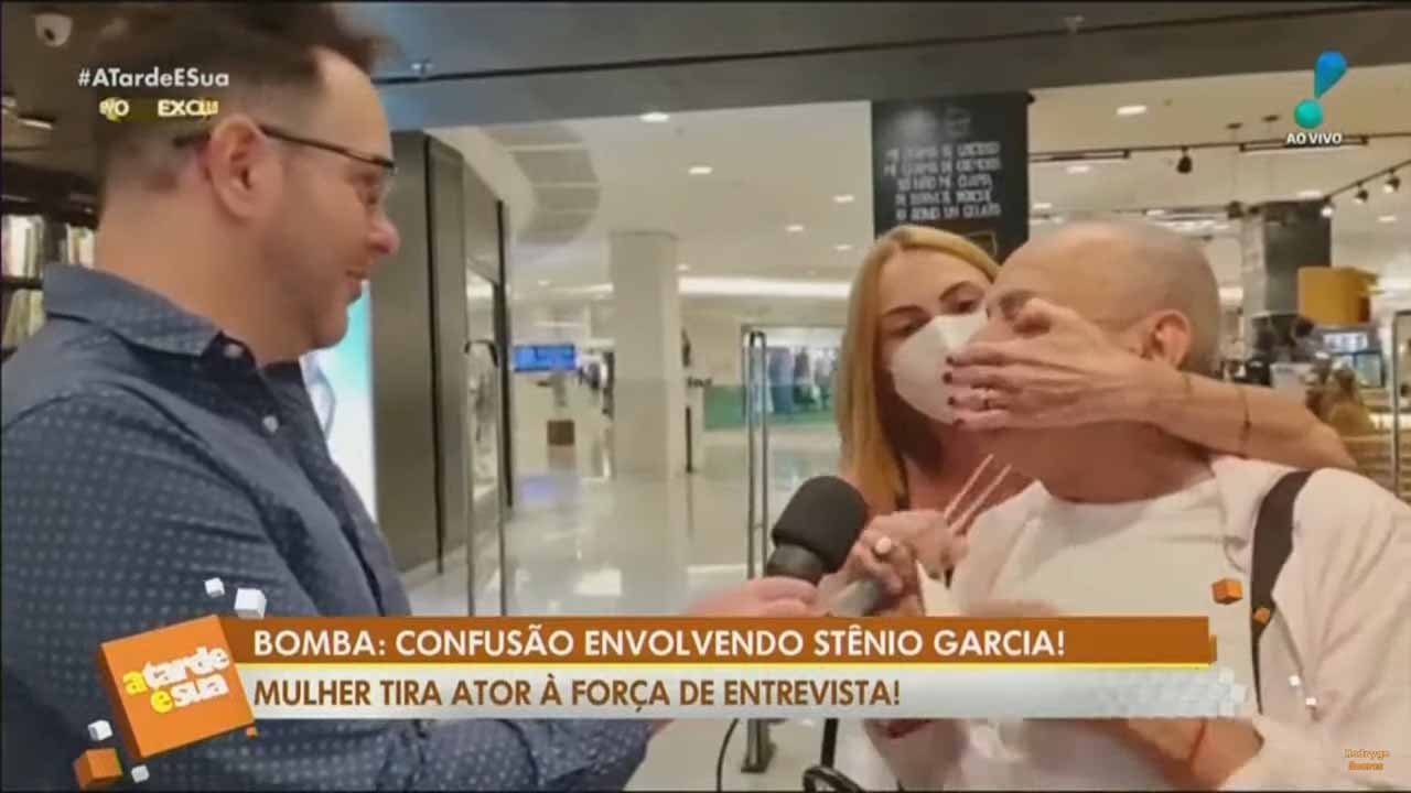Marilena Saadi tapando a boca de Stenio Garcia diante de repórter com microfone