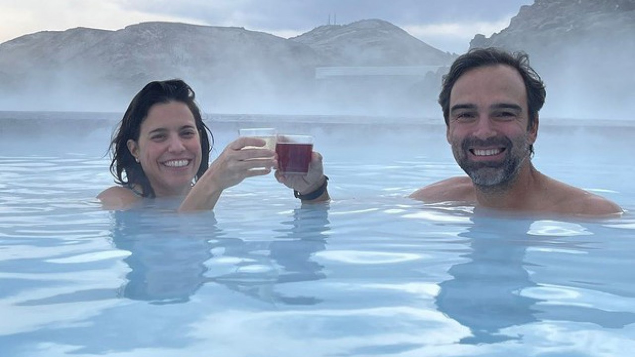 Tadeu Schmidt e a esposa Ana Cristina brindando dentro de piscina aquecida na Islândia