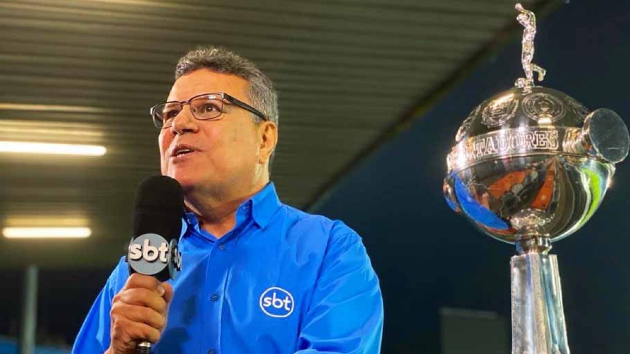 Téo José segurando o microfone ao lado da Taça Libertadores da América
