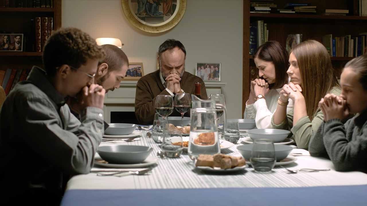 Cena do filme Terra Santa onde aparece pessoas orando em torno de uma mesa