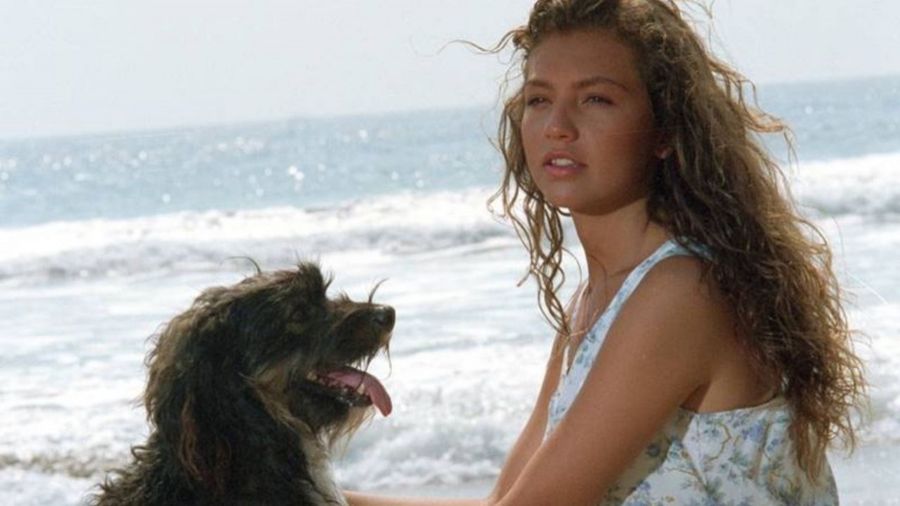 Thalía e cachorro posando para foto em praia