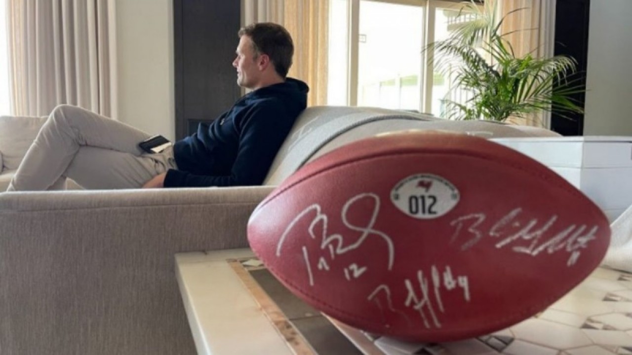 Tom Brady no sofá e com bola de futebol americano