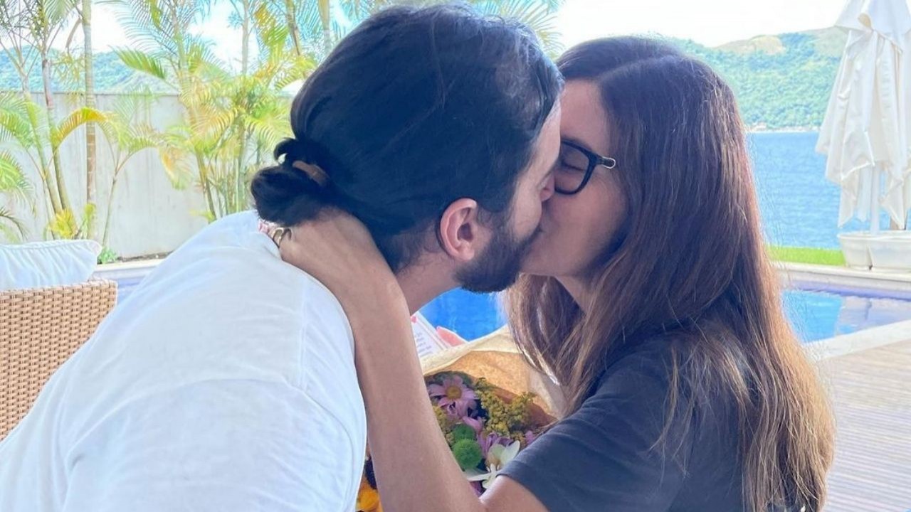 Fátima Bernardes e Túlio Gadêlha se beijando e segurando buquê de flores