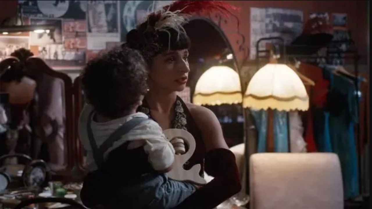 A atriz Duda Brack, como a personagem Iolanda, assustada com o filho nos braços em cena de Além da Ilusão