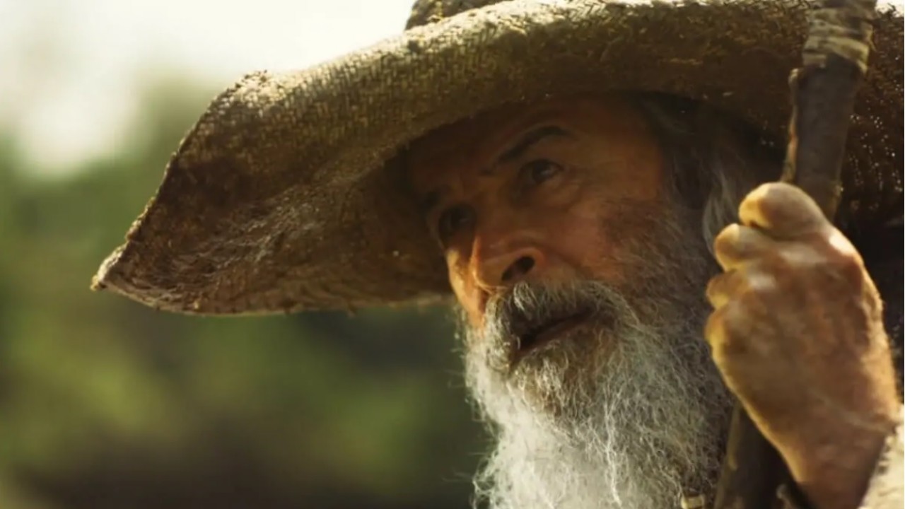 O ator Osmar Prado, como Velho do Rio, segurando um cajado em cena de Pantanal