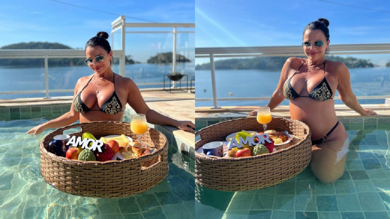 Viviane Araújo, sentada na beira da piscina, com uma cesta de café da manhã com suco e frutas