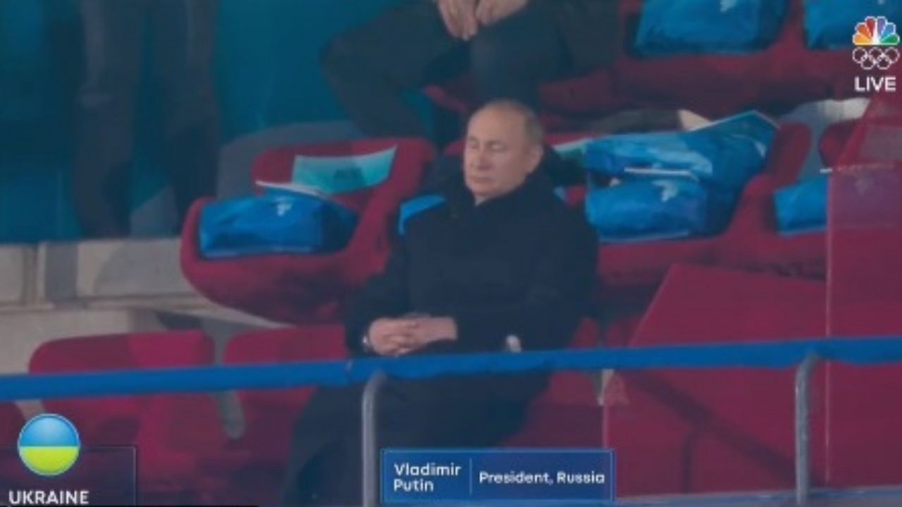 Vladimir Putin de roupa preta, cochilando com as mãos unidas, sentado em cadeira vermelha